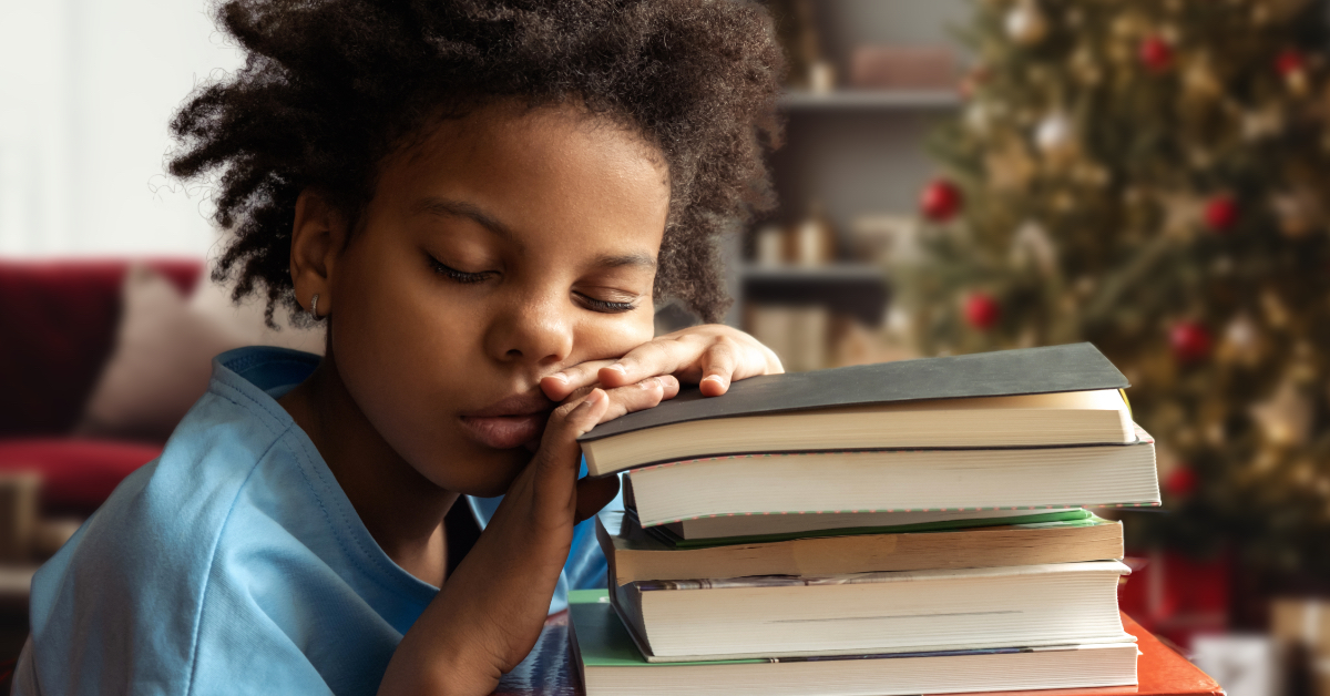 A tired student rests their head on a stack of textbooks.