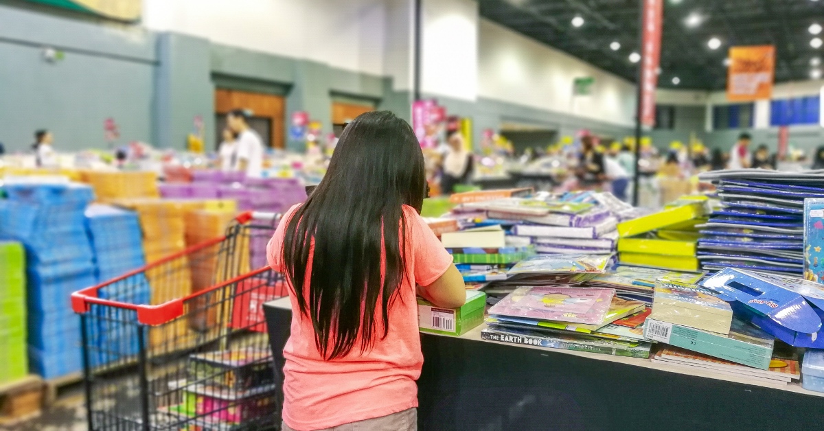 A young girl looking at books at a homeschool convention booth.