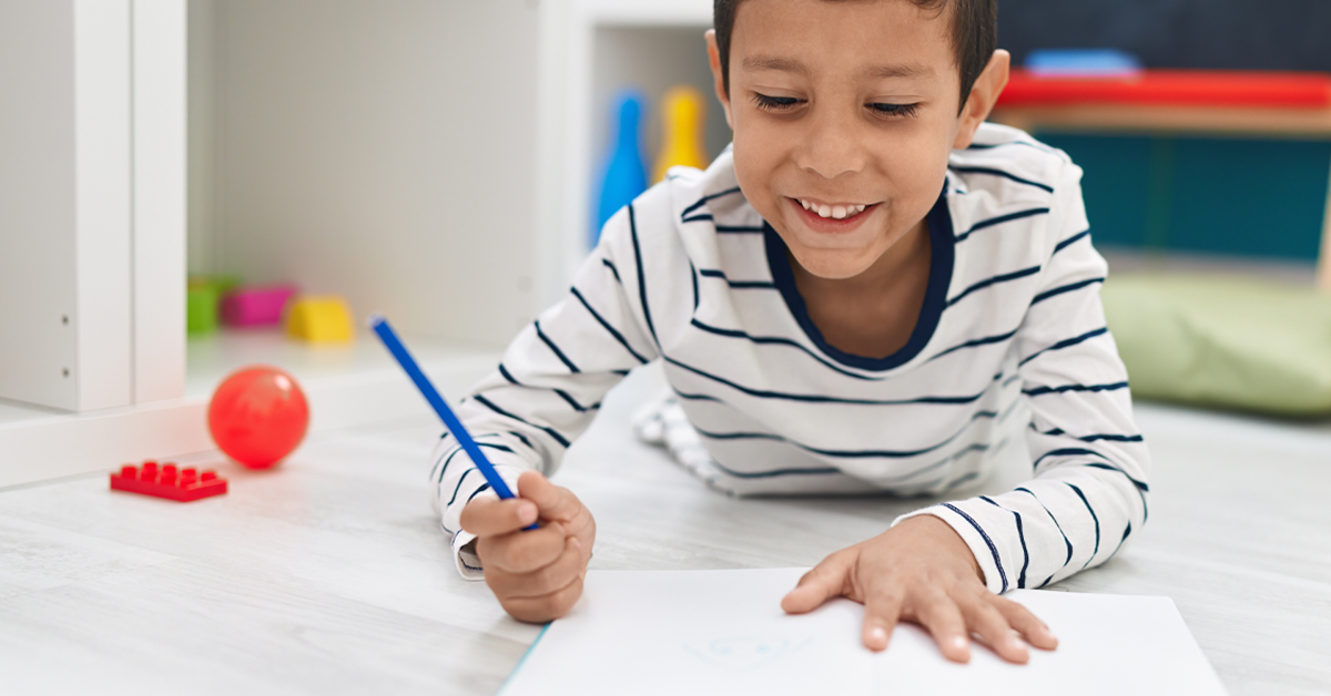 A young boy doing homework on the floor.